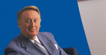 Fordham alumnus Vin Scully, the legendary sportscaster and Voice of the Dodgers, wearing a blue sport coat and sitting in front of a blue background.