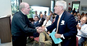 Joseph M. McShane shakes hands with Peter Calder at the 50th anniversary celebration of the Calder Center