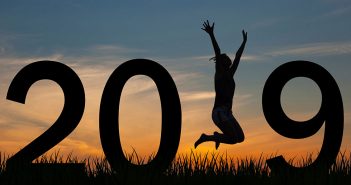 The numbers for 2019 in the sunset with a womn jumping in the place of the 1.