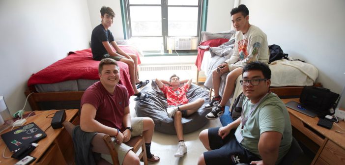 Five young students pose for a picture in a dorm.