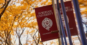 A Fordham flag in front of fall foliage