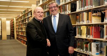 Father McShane and Michale Dowling standing together in front of books.