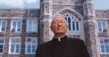 Father Joseph A. O'Hare, S.J. in front of Keating Hall.