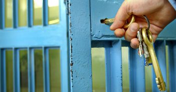 stock art of hand insterting key into jail cell