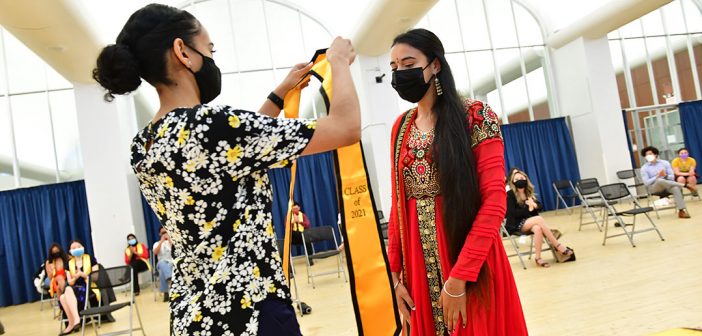 Student receiving yellow stole at AAPI graduation celebration in red dress