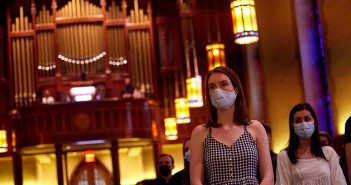 a woman with a mask stands in church