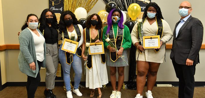 Students posing with diplomas in front of ballons at Black graduation celebration