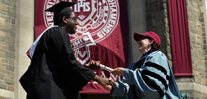 Dean Laura Auricchio giving a diploma to a graduate