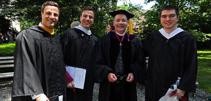 Four male graduates stand together for a photo