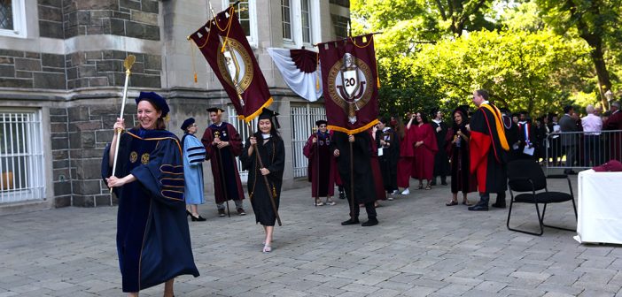 Graduates process across Keating Terrace with banners