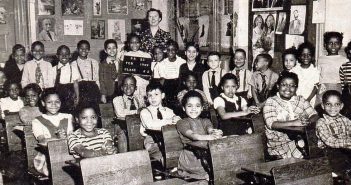 A black and white image of a group of children sitting in a classroom in the Bronx