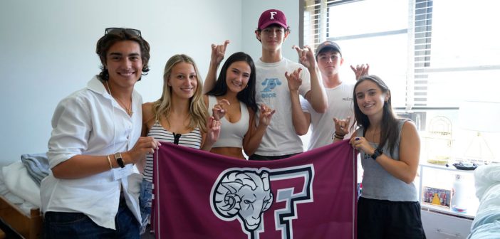Six students hold a maroon banner.